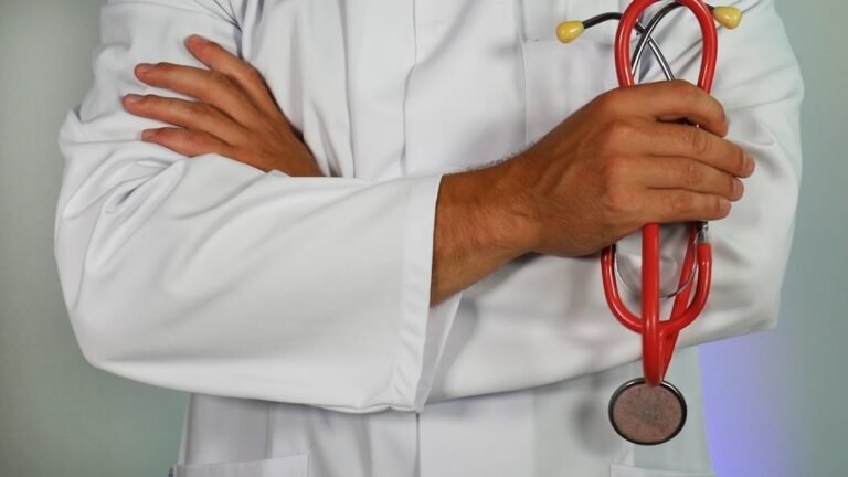 A man in a white coat holds a stethoscope, symbolizing knowledge management in healthcare.